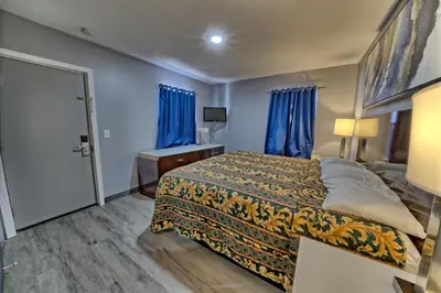 a bedroom with a bed with blue walls and blue curtains at Aqua View Motel in Panama City Beach