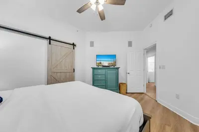 a white bedroom with a bed and a television at Legacy 104 in Santa Rosa Beach