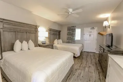 a hotel room with two beds and a flat screen tv at Flamingo Hotel & Tower in Panama City Beach