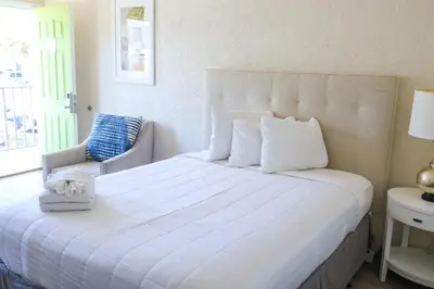 a bedroom with a large white bed and a chair at Flamingo Hotel & Tower in Panama City Beach