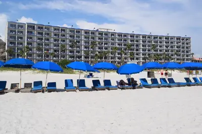 a row of blue chairs and umbrellas on a beach at Days Inn by Wyndham Panama City Beach Beachfront Resort in Panama City Beach
