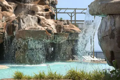 a water fall in a pool with a waterfall at Days Inn by Wyndham Panama City Beach Beachfront Resort in Panama City Beach