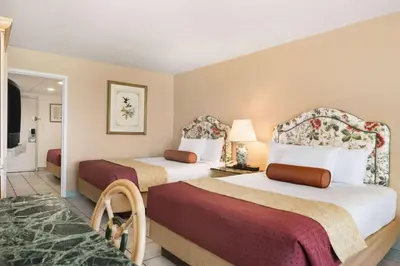 a hotel room with two beds and a television at Days Inn by Wyndham Panama City Beach Beachfront Resort in Panama City Beach