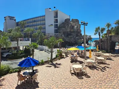 a patio with tables and umbrellas at a resort at Days Inn by Wyndham Panama City Beach Beachfront Resort in Panama City Beach