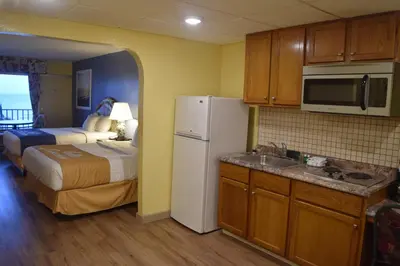 a room with a kitchen with a bed and a refrigerator at Days Inn by Wyndham Panama City Beach Beachfront Resort in Panama City Beach