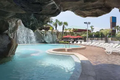 a swimming pool in a resort with a waterfall at Days Inn by Wyndham Panama City Beach Beachfront Resort in Panama City Beach