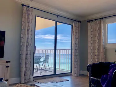 a living room with a sliding glass door with a view of the ocean at Regency Towers - beachfront condo in Panama City Beach
