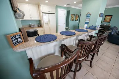 a kitchen with a bar with a row of chairs at Treasure Island 0212 in Panama City Beach