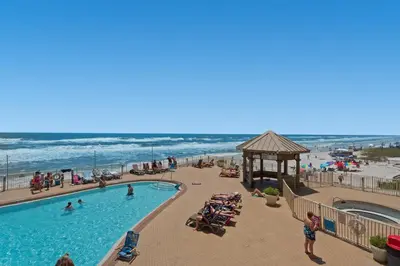 a swimming pool at a beach with a gazebo and the ocean at Treasure Island 0211 in Panama City Beach