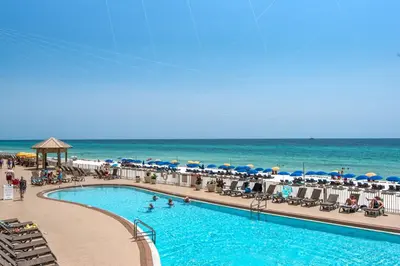 a swimming pool at the beach with umbrellas and the ocean at Treasure Island 0211 in Panama City Beach