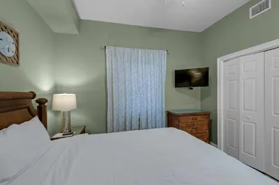 a bedroom with a white bed and a television at Treasure Island 0307 in Panama City Beach