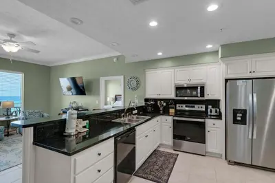 a kitchen with white cabinets and a stainless steel refrigerator at Treasure Island 0307 in Panama City Beach