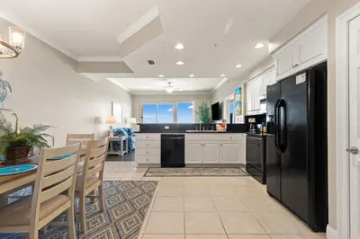 a kitchen with a black refrigerator and a table at Treasure Island 0403 in Panama City Beach