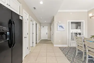 a hallway with a black refrigerator and a kitchen at Treasure Island 0403 in Panama City Beach