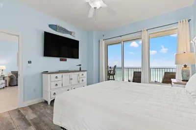 a bedroom with a white bed and a television at Treasure Island 0411 in Panama City Beach