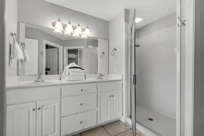 a white bathroom with two sinks and a shower at Treasure Island 0506 in Panama City Beach