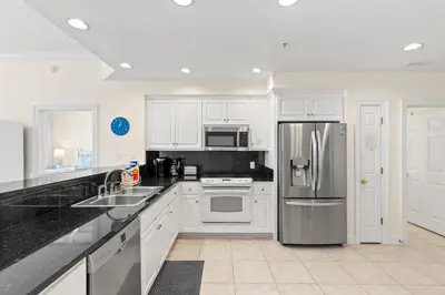a kitchen with white cabinets and a stainless steel refrigerator at Treasure Island 0503 in Panama City Beach
