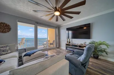 a living room with a couch and a large screen tv at Treasure Island 0906 in Panama City Beach