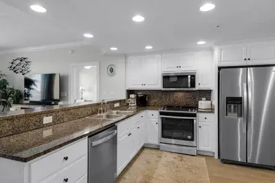 a kitchen with white cabinets and stainless steel appliances at Treasure Island 1003 in Panama City Beach