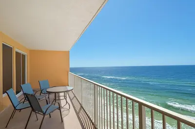 a balcony with chairs and a table and the ocean at Treasure Island 1003 in Panama City Beach