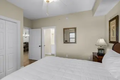 a bedroom with a large white bed and a mirror at Treasure Island 1003 in Panama City Beach