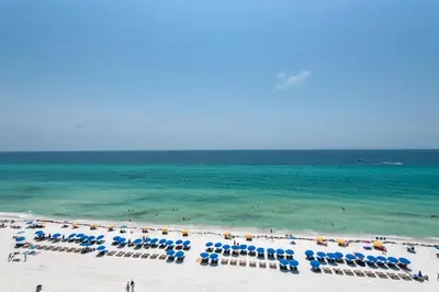 a beach with chairs and umbrellas and the ocean at Treasure Island 0809 in Panama City Beach