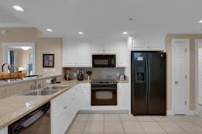 a kitchen with white cabinets and a black refrigerator at Treasure Island 0809 in Panama City Beach
