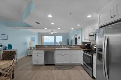 a kitchen with white cabinets and a stainless steel refrigerator at Treasure Island 1107 in Panama City Beach