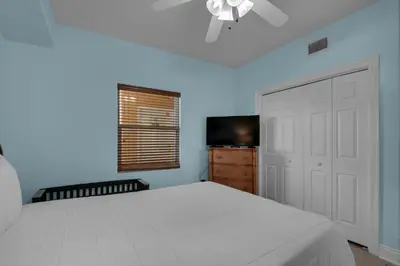 a bedroom with a white bed and a television at Treasure Island 1107 in Panama City Beach