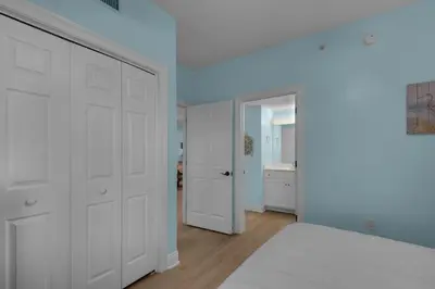 a white bedroom with a bed and a bathroom at Treasure Island 1107 in Panama City Beach