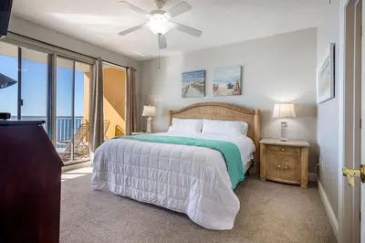 a bedroom with a large bed and a balcony at Treasure Island 1109 in Panama City Beach