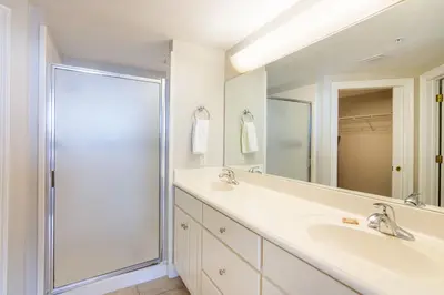 a white bathroom with a shower and a sink at Treasure Island 1109 in Panama City Beach