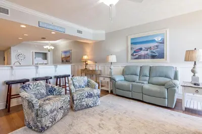 a living room with a couch and chairs and a bar at Treasure Island 1109 in Panama City Beach