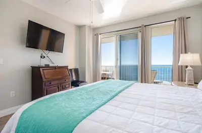 a bedroom with a large bed with a flat screen tv at Treasure Island 1109 in Panama City Beach