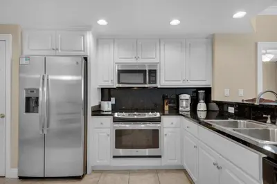 a kitchen with white cabinets and a stainless steel refrigerator at Treasure Island 1208 in Panama City Beach