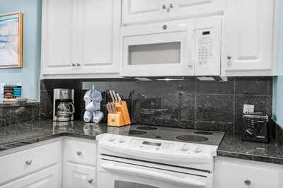 a white kitchen with a stove and a microwave at Treasure Island 1905 in Panama City Beach