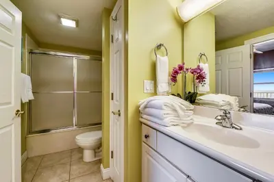 a bathroom with a sink and a toilet and a mirror at Treasure Island 2202 in Panama City Beach