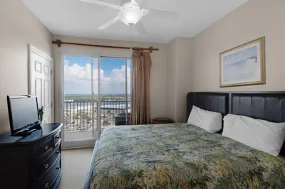 a bedroom with a bed and a window with a balcony at Treasure Island 2312 in Panama City Beach