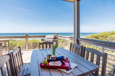 a table on a deck with a view of the ocean at Pelican Paradise - Unit A in Seacrest
