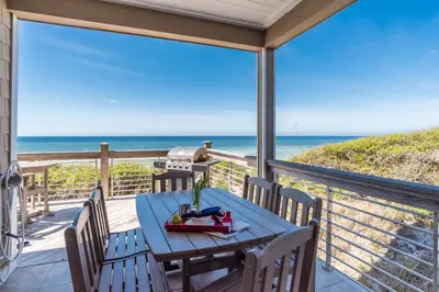 a patio with a table and chairs and the ocean at Pelican Paradise - Unit A in Seacrest