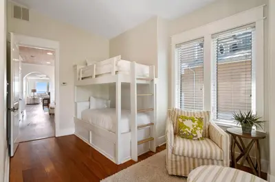 a bedroom with white bunk beds and a chair at Pelican Paradise Unit B in Seacrest