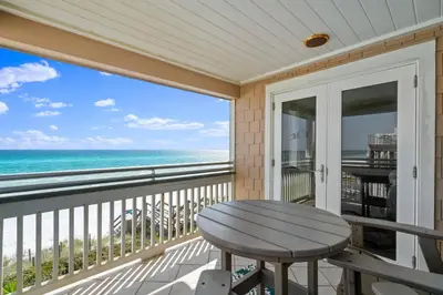 a balcony with a table and a view of the ocean at Pelican Paradise Unit B in Seacrest