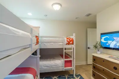 a bedroom with bunk beds and a desk and a tv at Pelican Paradise in Seacrest