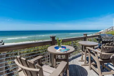 a balcony with tables and chairs and the beach at Pelican Paradise in Seacrest