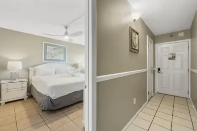 a bedroom with a white bed and a hallway at The Summit 1128 in Panama City Beach