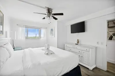 a white bedroom with a bed and a ceiling fan at The Summit 702 in Panama City Beach