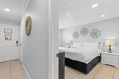 a white bedroom with a bed and a hallway at The Summit 1409 in Panama City Beach