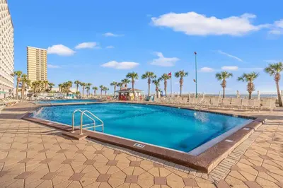 a swimming pool next to a beach with palm trees at The Summit 1409 in Panama City Beach