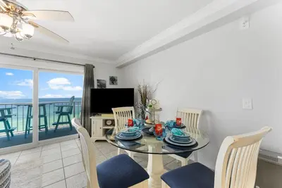 a dining room with a table and chairs and a balcony at The Summit 1130 in Panama City Beach