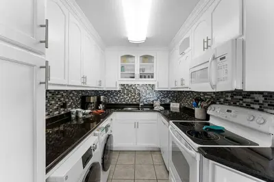 a white kitchen with black counter tops and white cabinets at The Summit 1130 in Panama City Beach